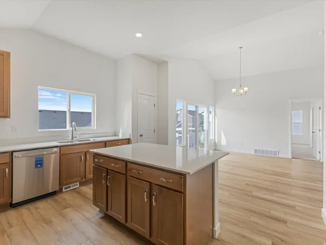 Kitchen featuring wood-finish flooring, stainless steel appliances, a center island with countertop space, and brown cabinetry
