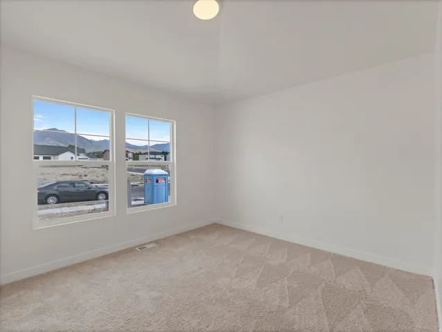 Carpeted flooring, white painted walls, two windows, recessed ceiling light