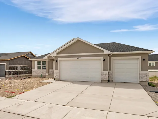 Stucco exterior with stone veneer accents, two-car garage, single-car garage, and concrete driveway