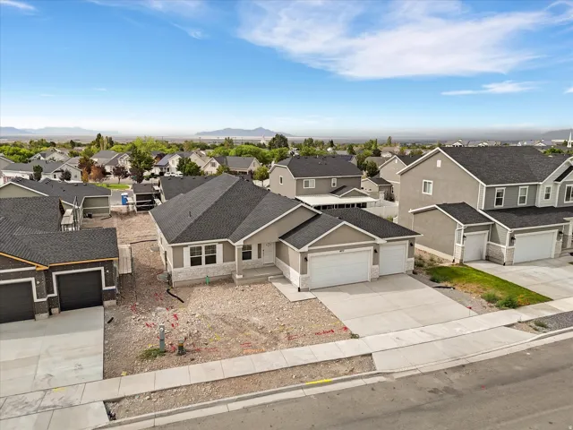 Single-story residence featuring a dark shingle roof, light-toned stucco siding, and stone-finish accents