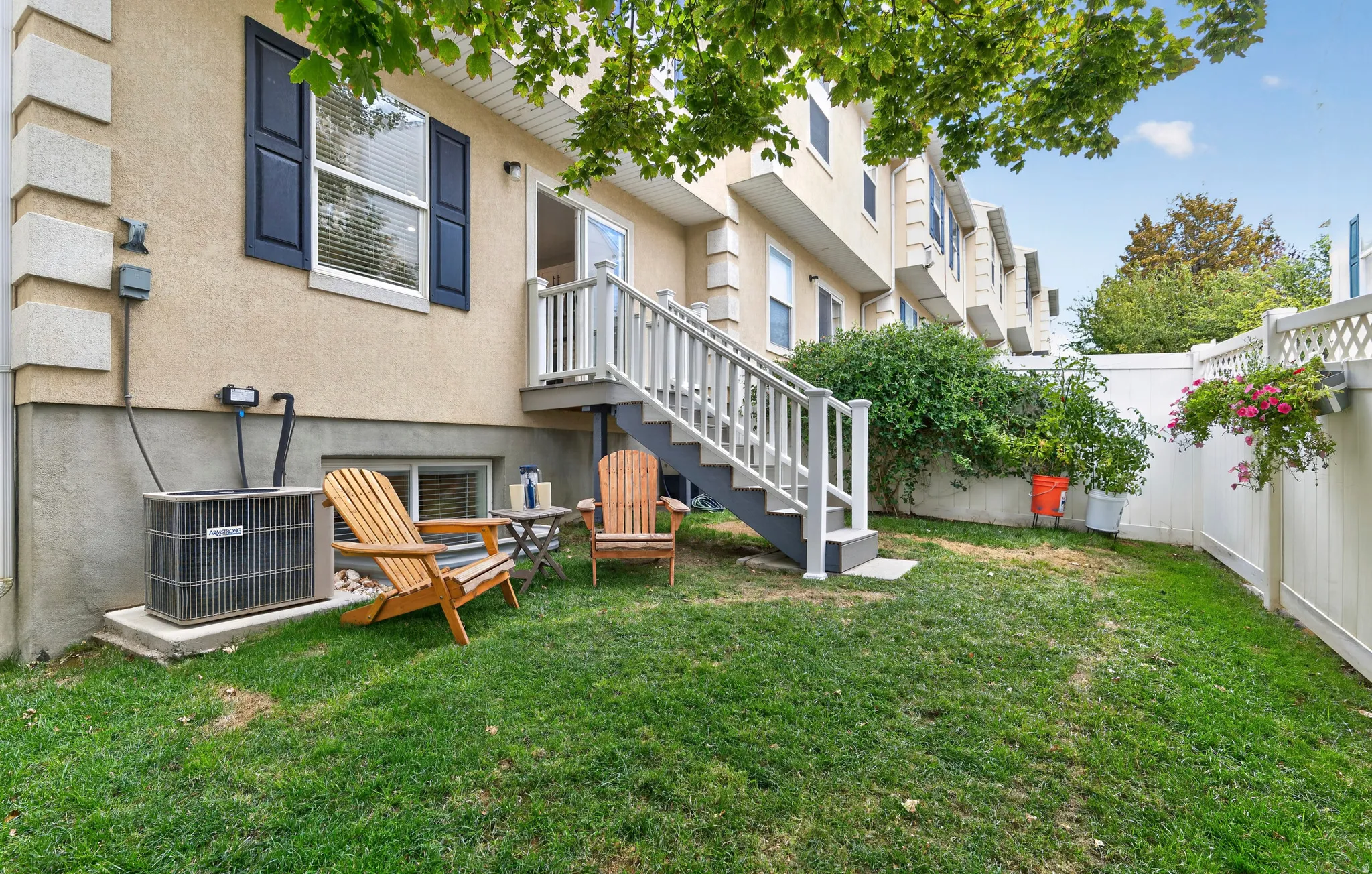 Fenced backyard with a grassy area and a deck accessible via stairs