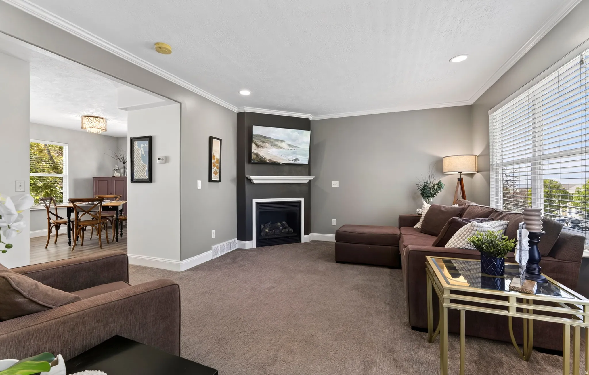 Living space featuring a corner fireplace with a white mantel, recessed lighting, and crown molding