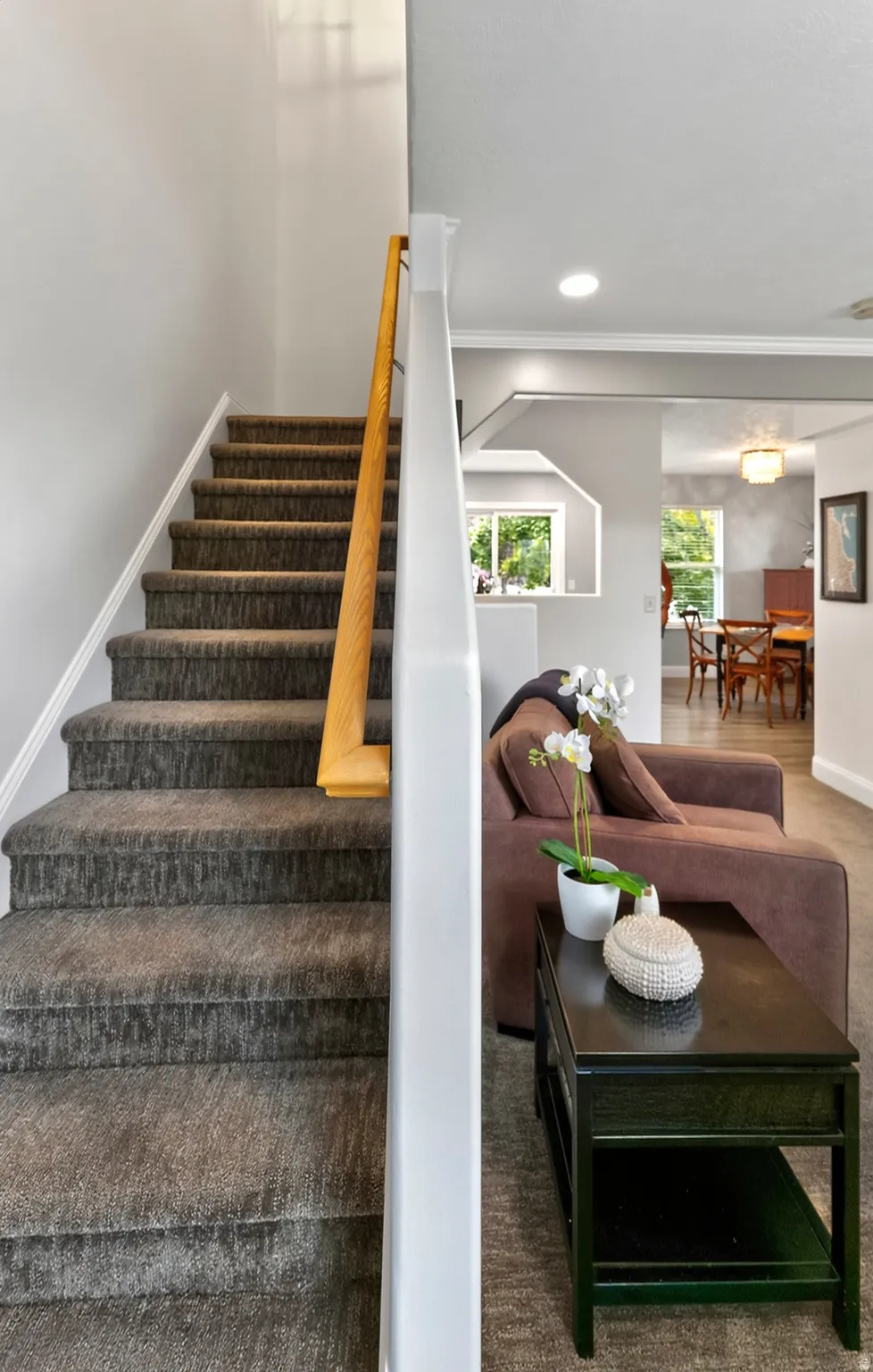 Staircase with carpeted treads and a natural wood handrail