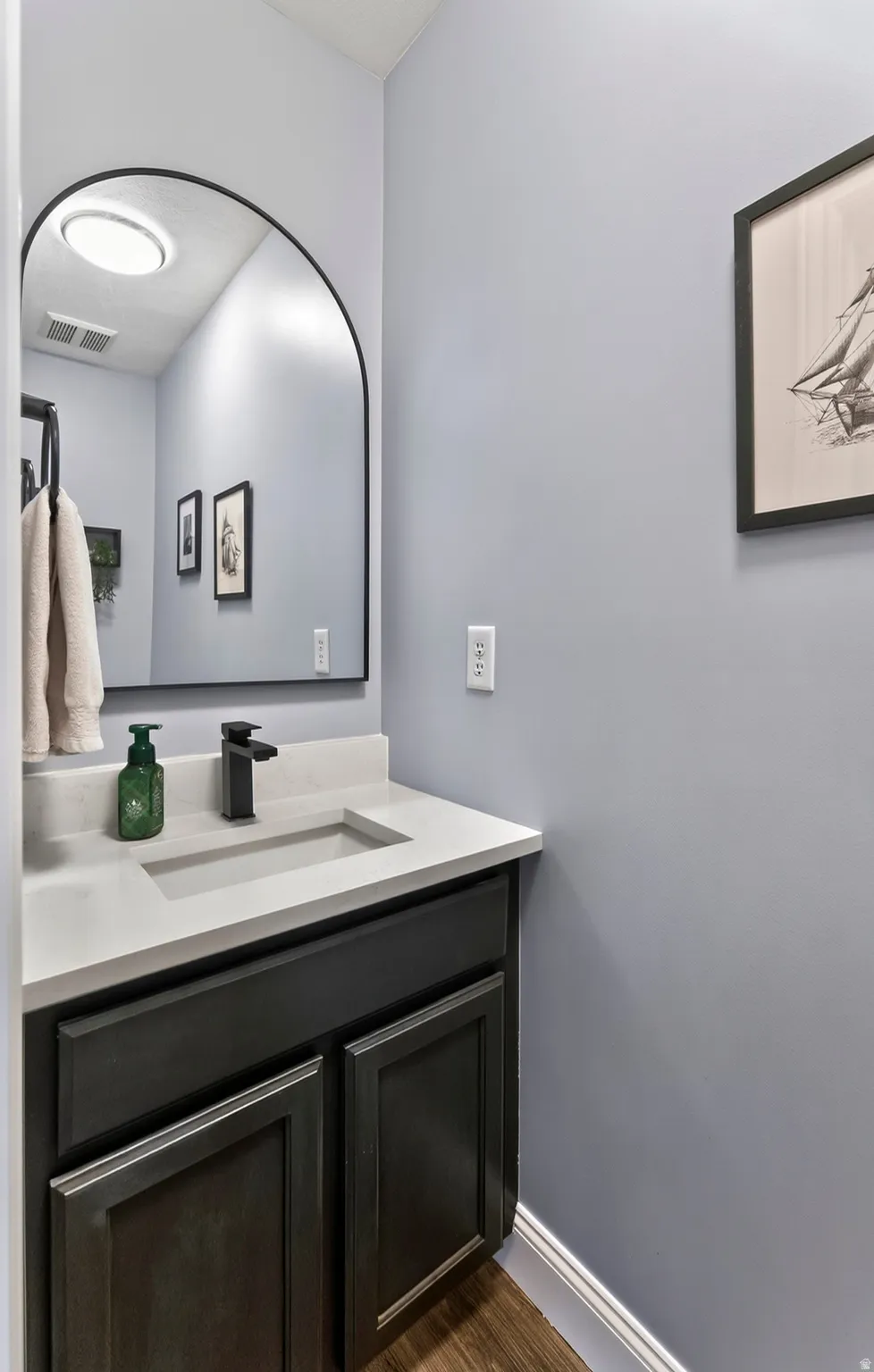 Vanity with a light-colored countertop, integrated rectangular sink, and matte black faucet