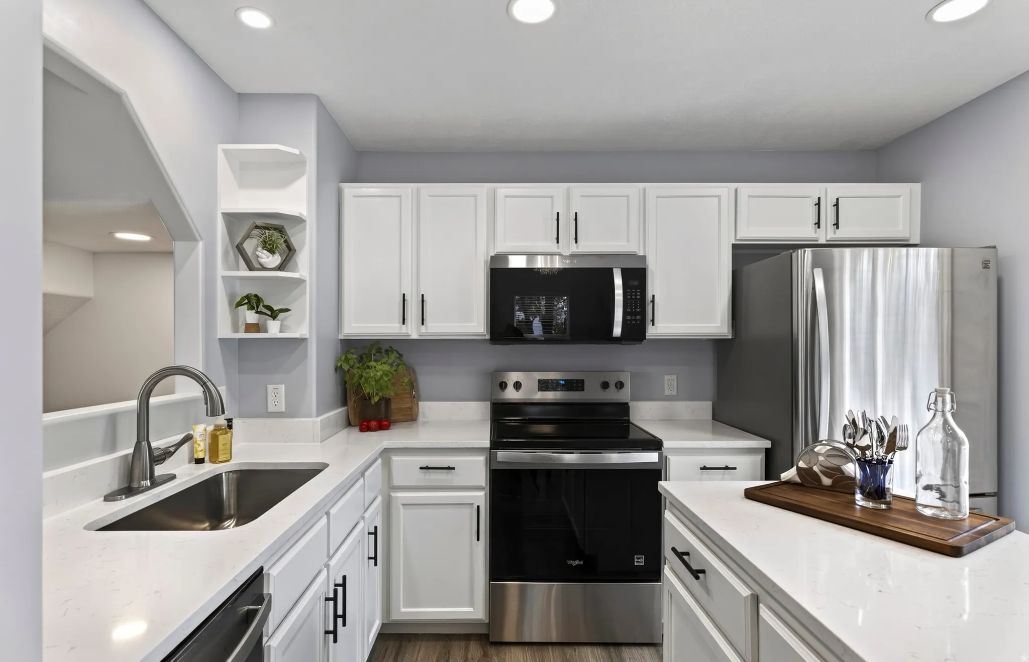 Modern kitchen featuring white cabinetry, brand new quartz countertops, stainless steel appliances, a stainless steel sink, and wood-finish flooring