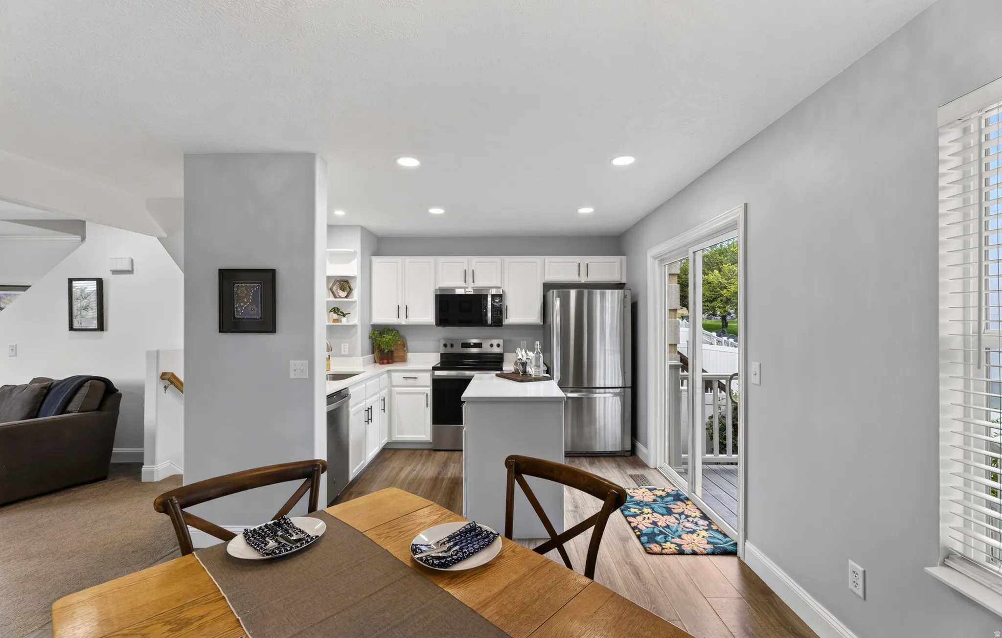 Kitchen with white cabinetry, stainless steel appliances, and wood-finish flooring