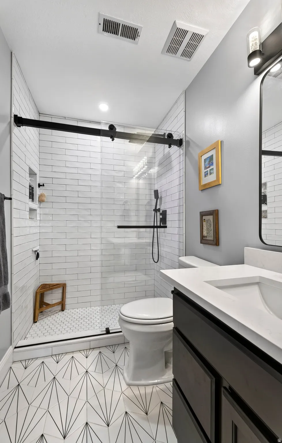 Walk-in shower with clear glass door, white subway tile surround, and black fixtures