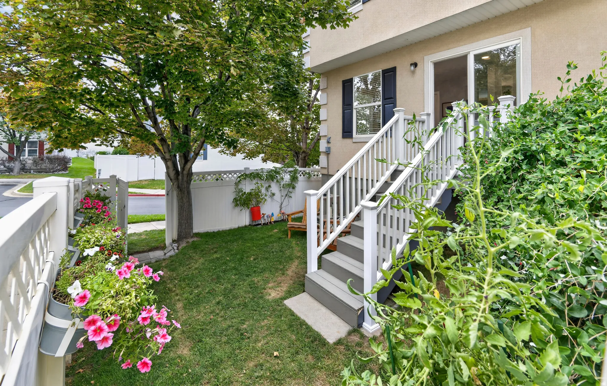 White vinyl fence enclosing a green lawn, mature tree, and a built-in staircase leading to a sliding glass door