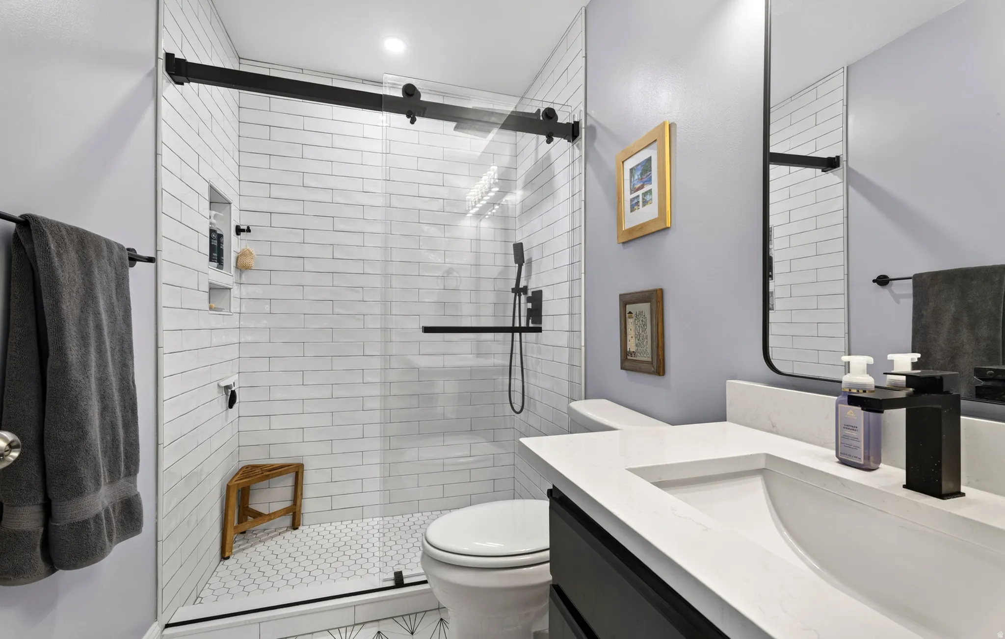 Master bathroom.Glass-enclosed shower with subway tile surround, hexagon tile flooring, and integrated shower niche