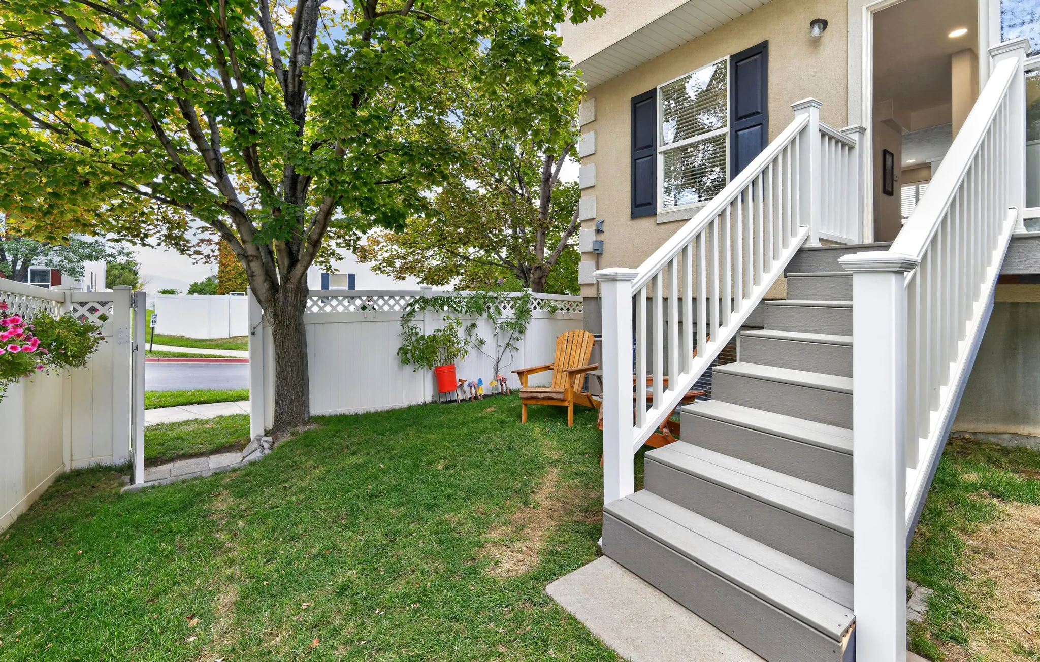 Private backyard space with mature tree and white privacy fencing