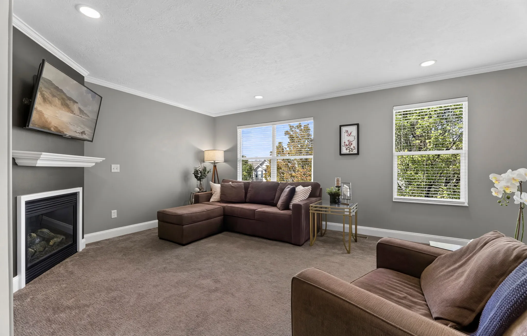 Recessed lighting, crown molding, and a corner fireplace with a white mantel