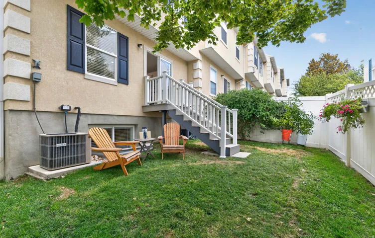 Fenced backyard with a grassy area and a deck accessible via stairs