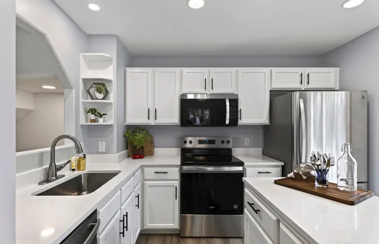 Modern kitchen featuring white cabinetry, brand new quartz countertops, stainless steel appliances, a stainless steel sink, and wood-finish flooring