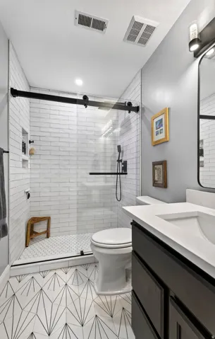 Walk-in shower with clear glass door, white subway tile surround, and black fixtures