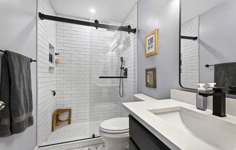 Master bathroom.Glass-enclosed shower with subway tile surround, hexagon tile flooring, and integrated shower niche