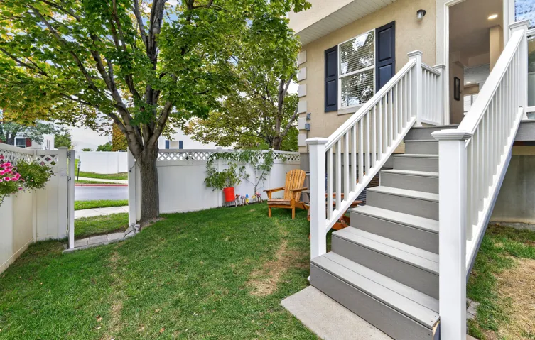 Private backyard space with mature tree and white privacy fencing