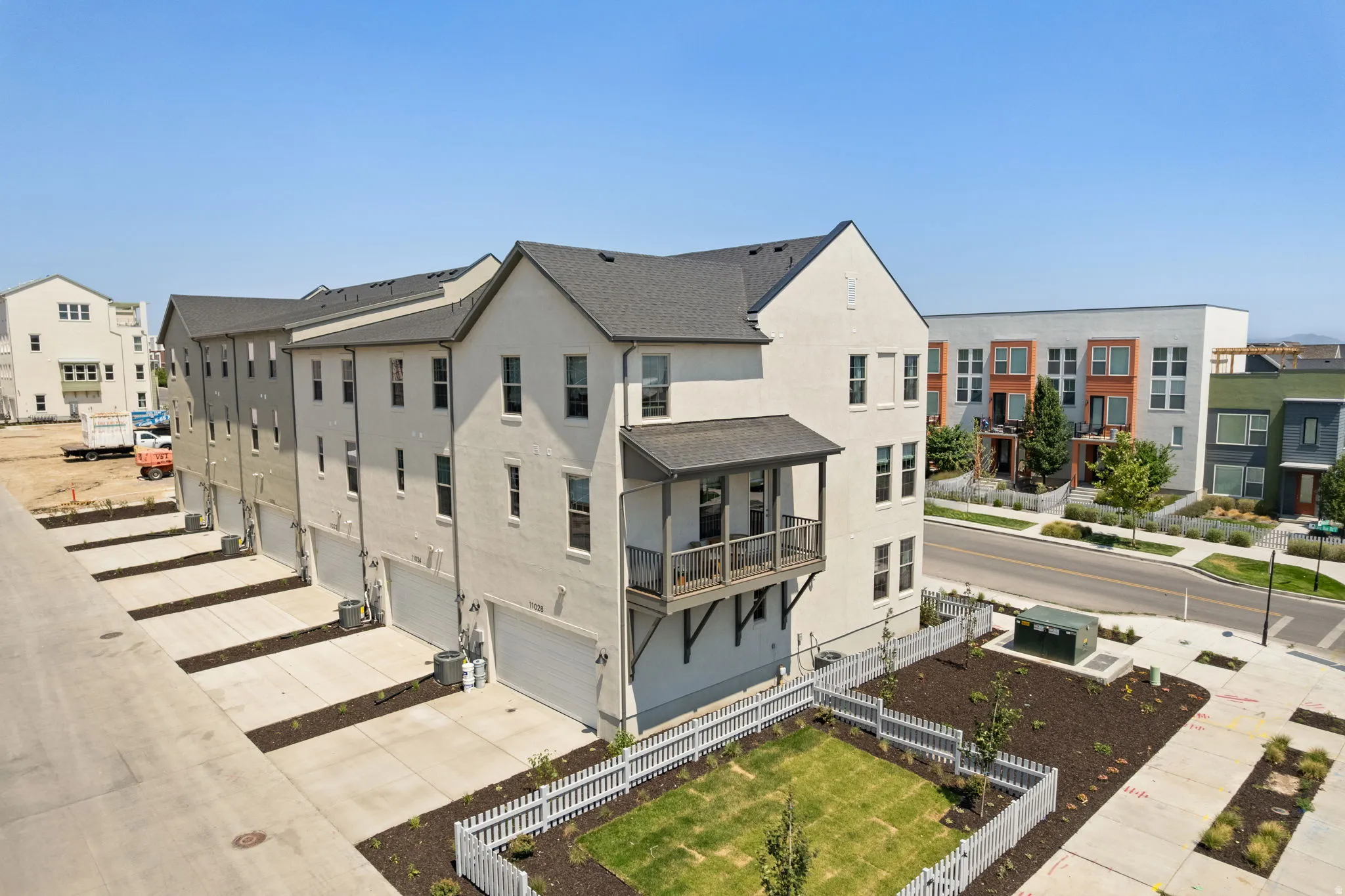 Multi-story townhome with a private balcony, attached two-car garage, and a fenced backyard