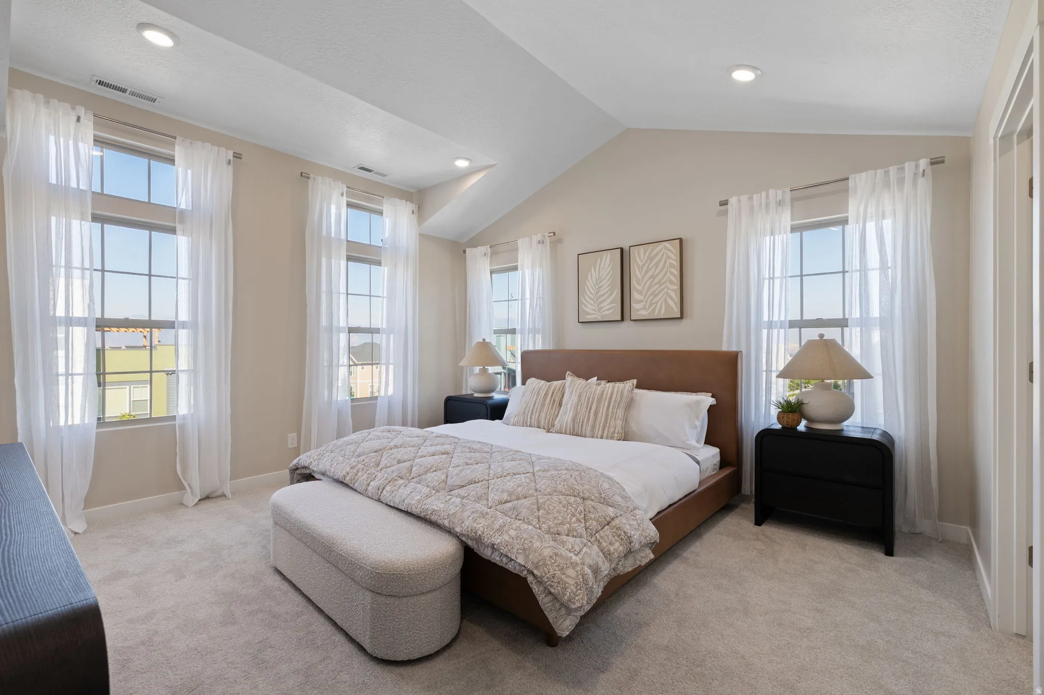 Vaulted ceiling with recessed lighting, large paneled windows, light-toned carpeting, and a built-in closet