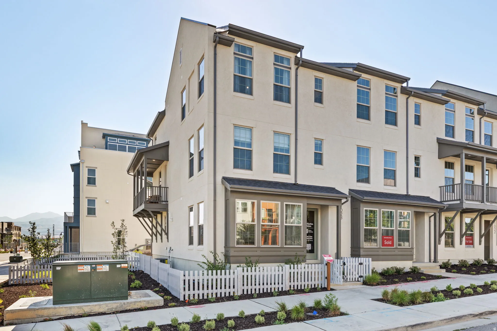 Multi-story stucco exterior with multiple windows, individual balconies, and a white picket fence