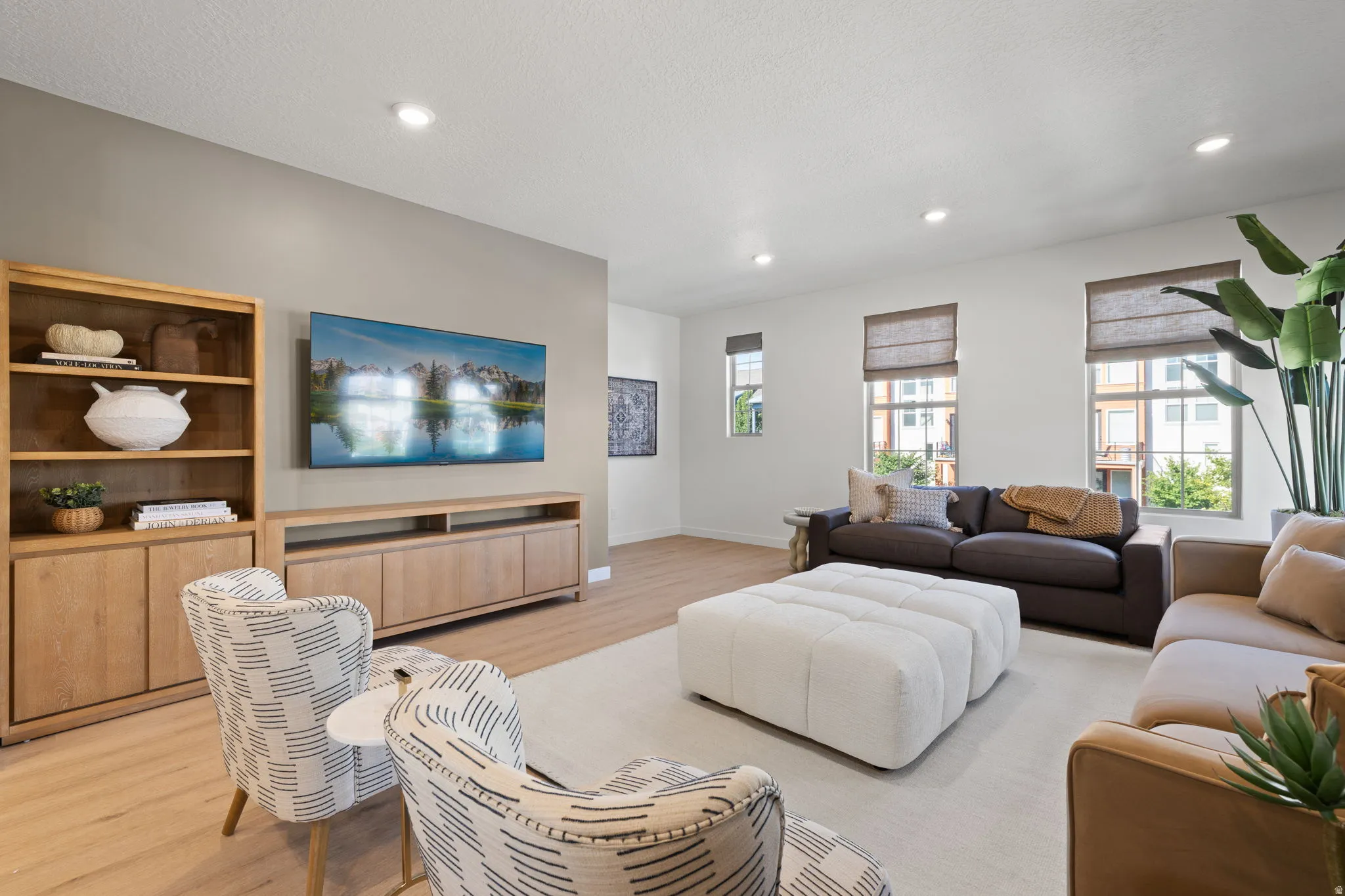 Recessed lighting, wood-finish flooring, built-in media console, multiple windows with window treatments, and light wall paint
