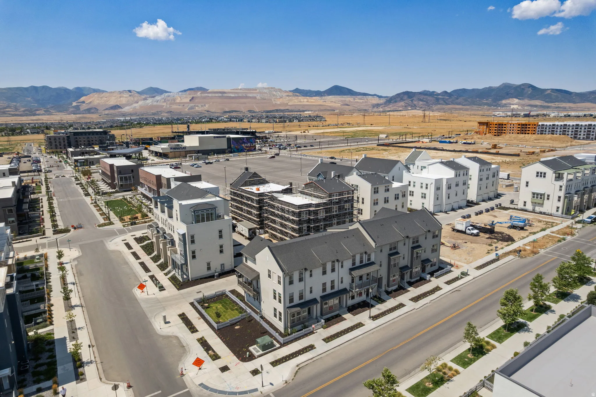 Modern townhome community with a light-colored exterior, dark gray roofing, and landscaped common areas, situated on paved streets