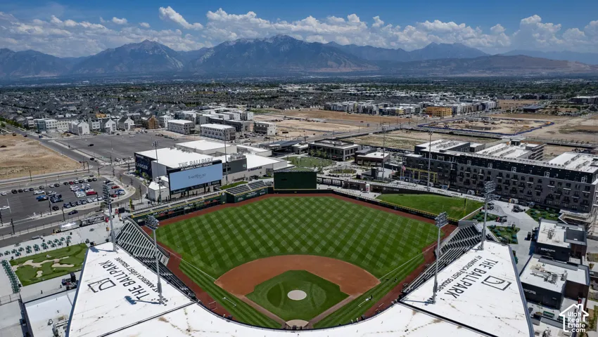 Baseball stadium with manicured green field, surrounding urban development, and distant mountains