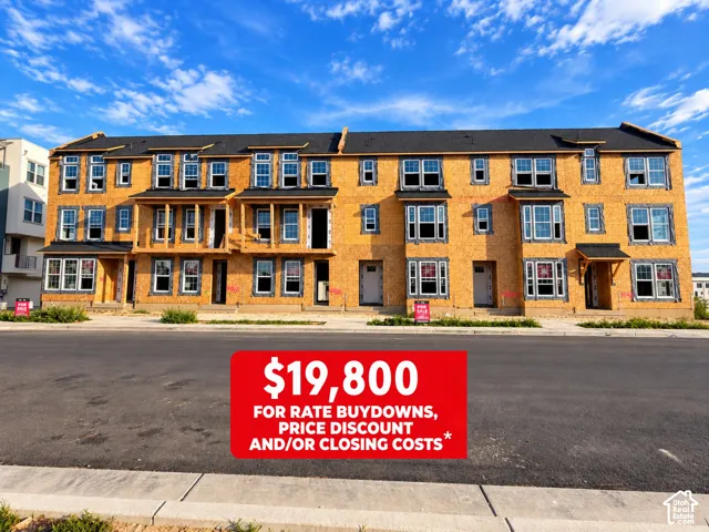 Three-story multi-unit structure featuring installed window frames and exterior sheathing with asphalt shingle roofing