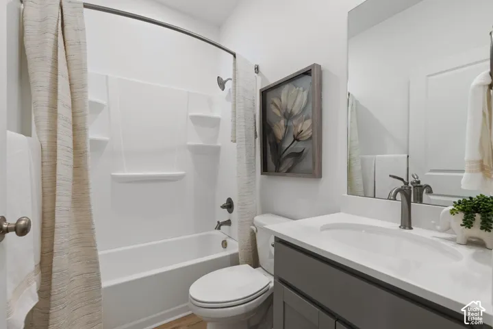Bathroom featuring a white tub/shower combination, a gray vanity with a white countertop and integrated sink, a frameless mirror, and wood-finish flooring