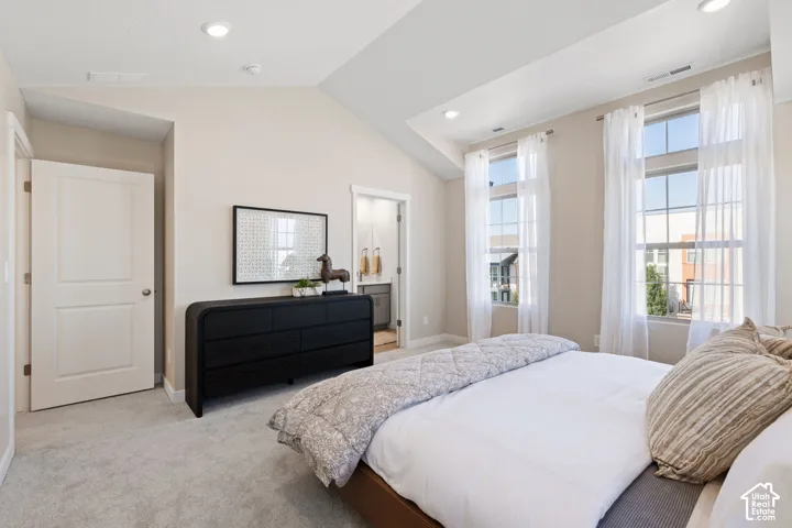 Vaulted ceiling, recessed lighting, two large windows, light-colored carpeting, and a white paneled door