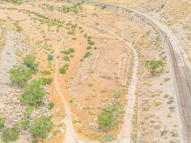 Expansive land featuring a natural landscape, established trees, and a railway line