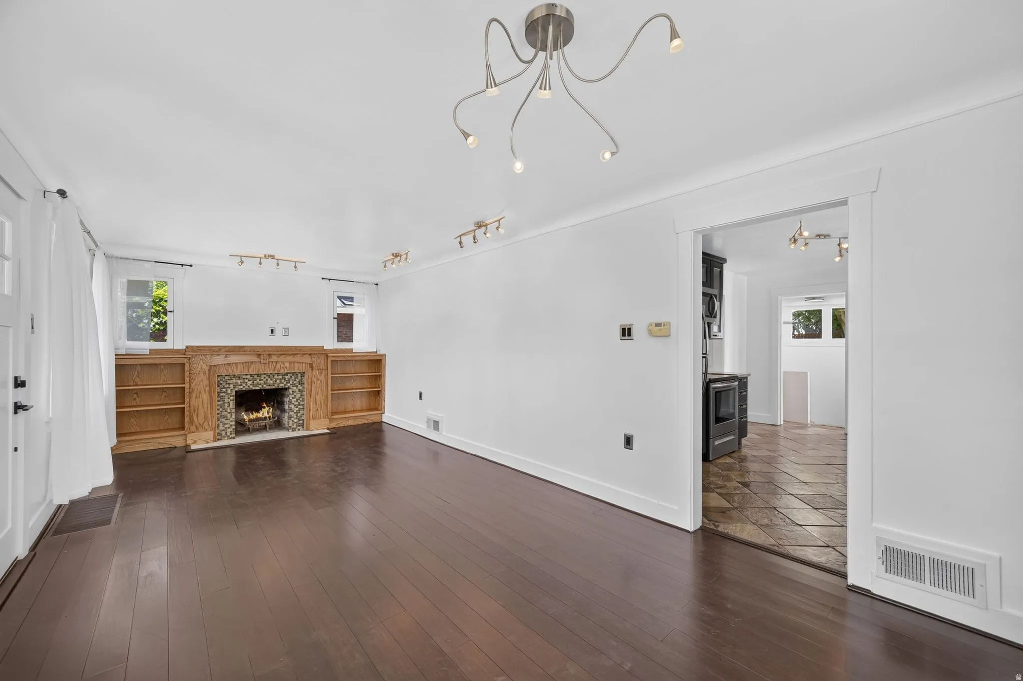 Wood-finish flooring throughout, featuring a fireplace with a decorative tile surround and wood mantel