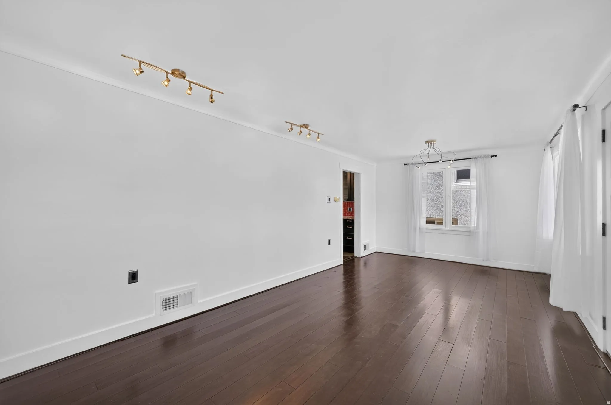 Hardwood-finish flooring, white walls, two windows, track lighting, and a contemporary ceiling fixture