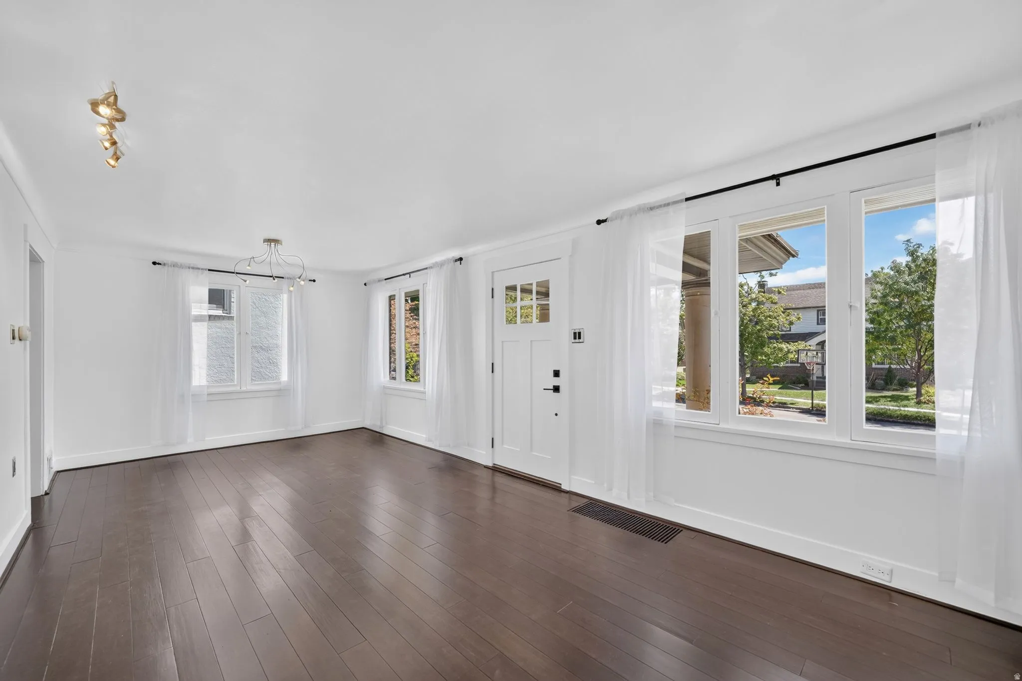 Dark wood-finish flooring, white walls, multiple windows, recessed lighting, and a contemporary ceiling fixture