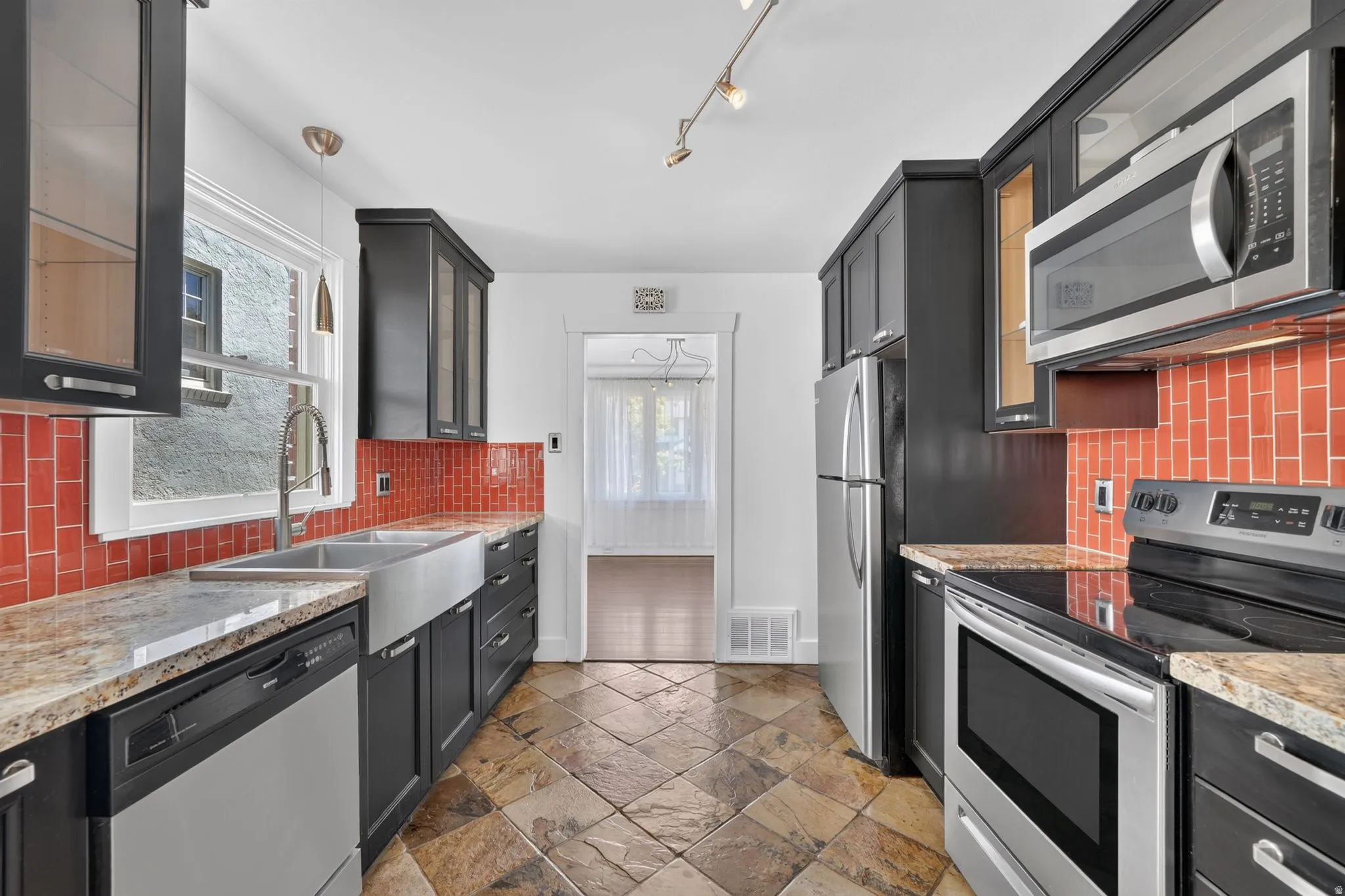 Kitchen with tiled flooring, dark cabinetry, and stone countertops