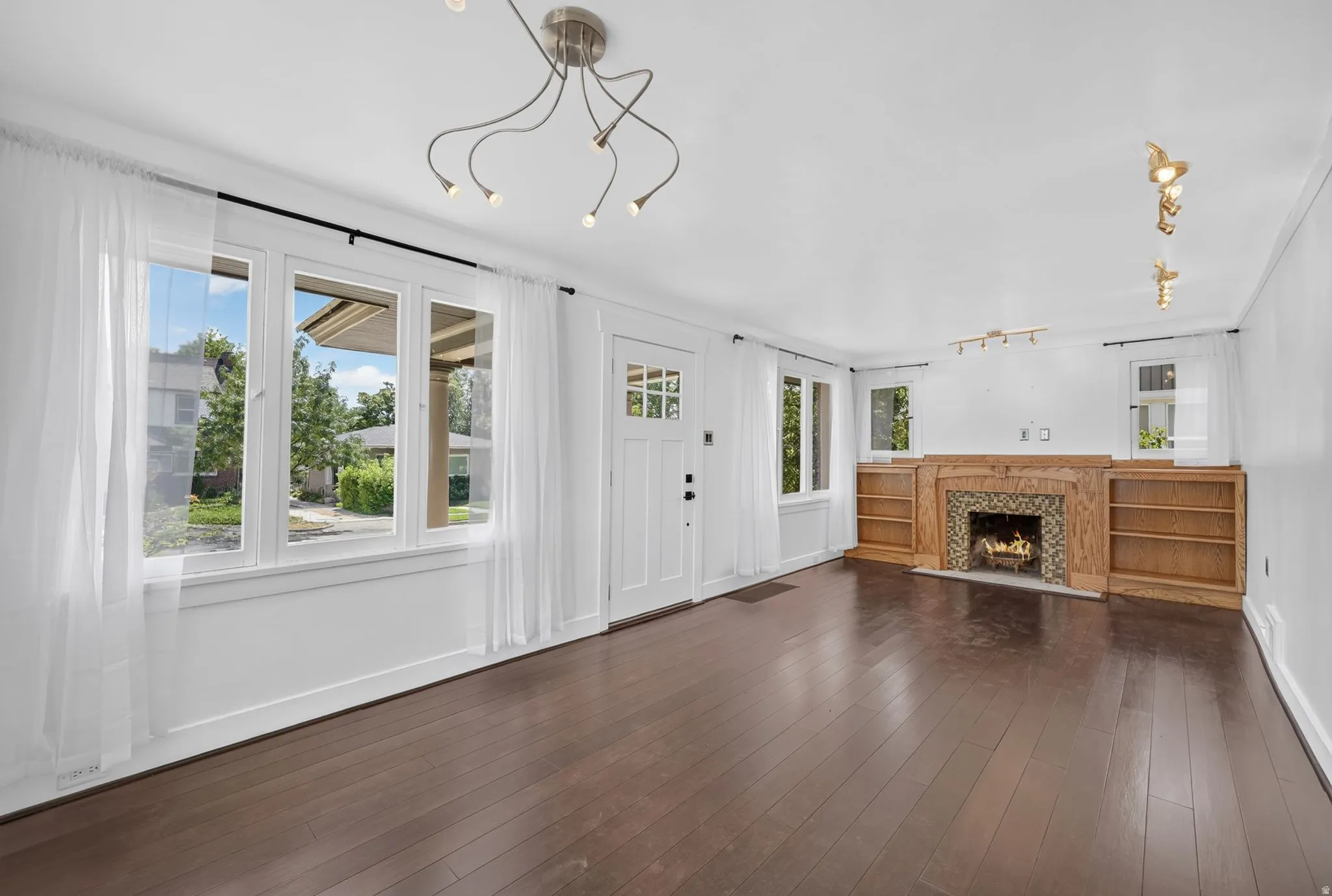 Dark wood-finish flooring, white walls, and a multi-pane front door
