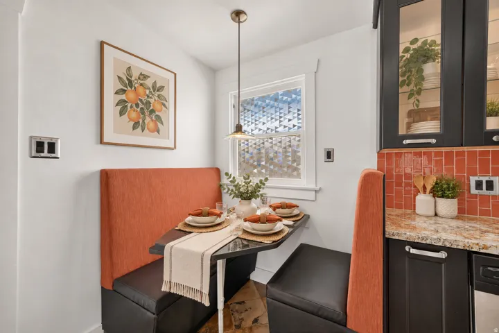 Built-in banquette seating with under-seat storage, a pendant light fixture, granite countertops, and a tiled backsplash