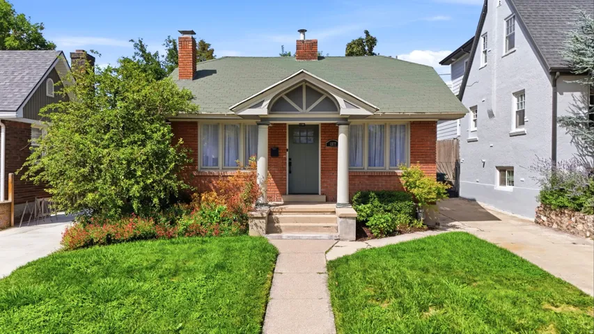 Brick exterior with a green shingle roof, featuring a covered entry porch with arched detailing