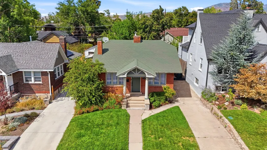 Brick exterior with a green shingle roof, established landscaping, and a concrete driveway