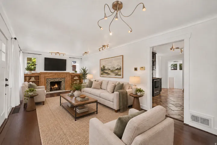 Living room with dark wood-finish flooring, a decorative fireplace with a wood mantle and tile surround, and built-in shelving