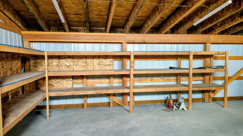 Built-in wood shelving units, corrugated metal wall panels, exposed wood ceiling joists, and concrete flooring