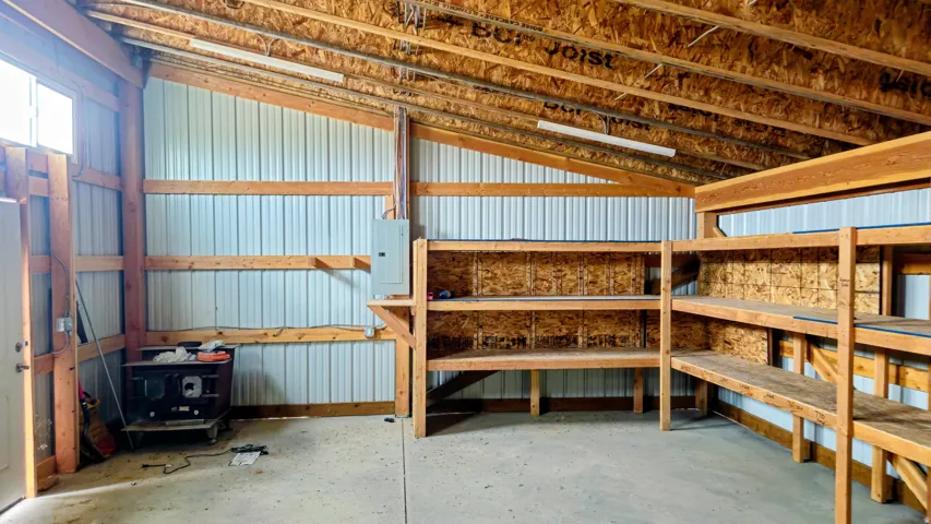 Built-in wooden shelving units, exposed wooden rafters, corrugated metal interior walls, concrete flooring, and an electrical service panel