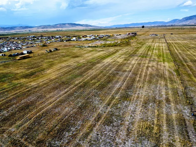 Expansive open field with distant mountains and a partially visible fence line