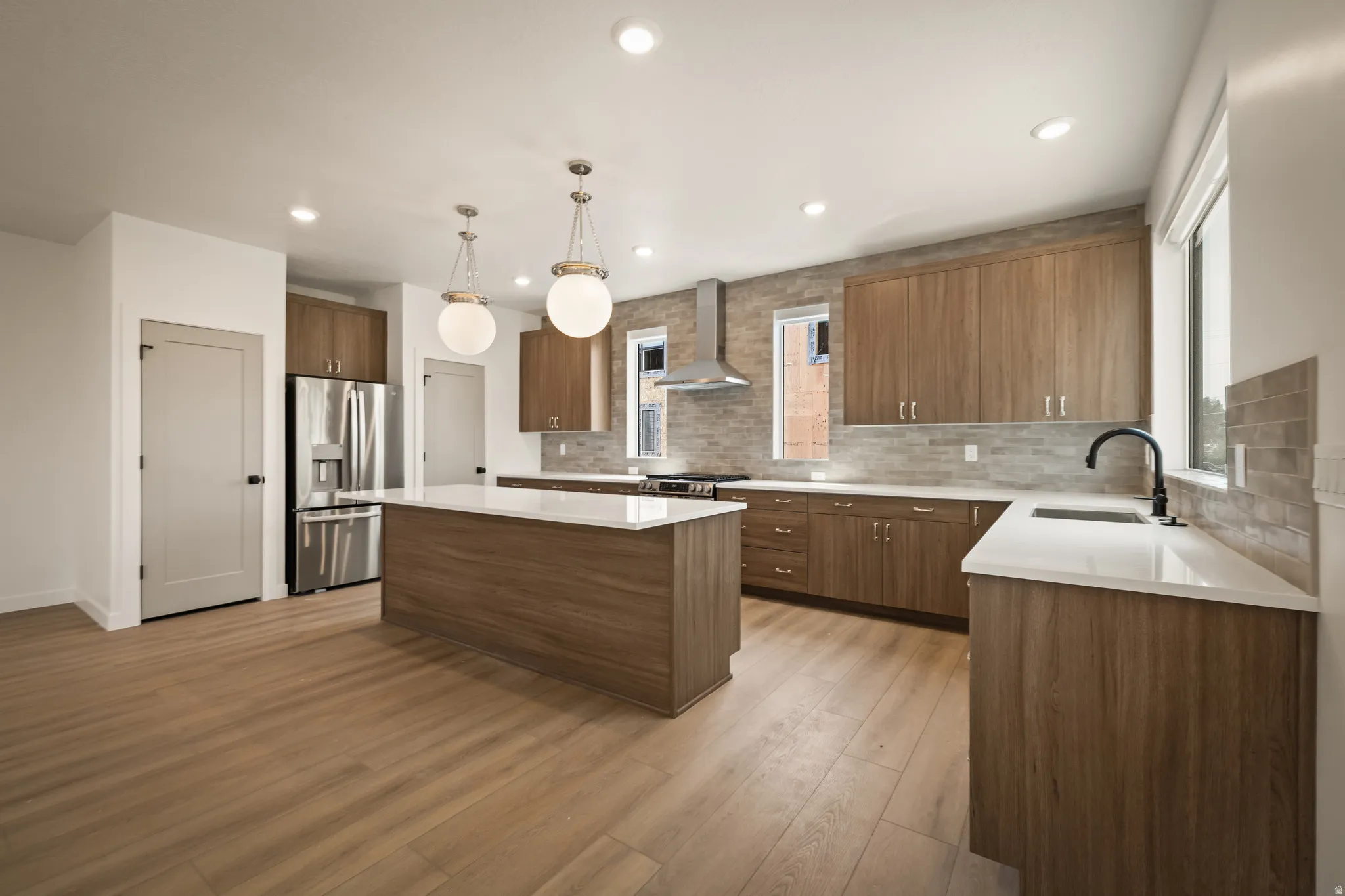 Spacious kitchen featuring wood-finish cabinetry, a large kitchen island with a white countertop, stainless steel appliances, and wood-finish flooring