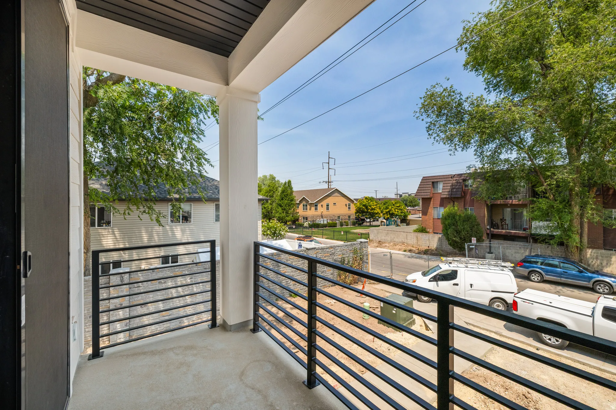 Private balcony featuring a concrete floor, white support columns, and black horizontal railings