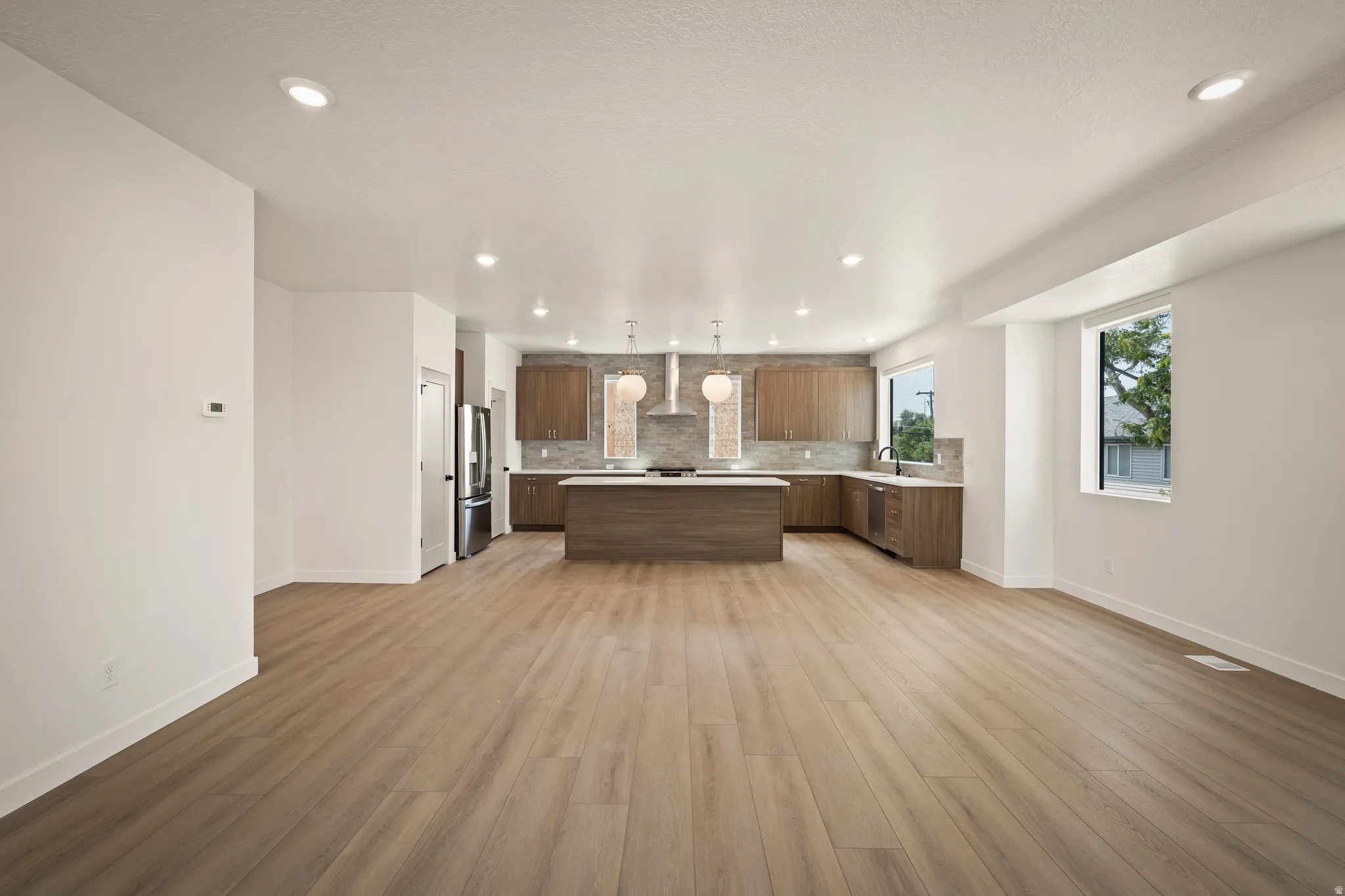 Spacious open-concept living area with wood-finish flooring, recessed lighting, and ample natural light
