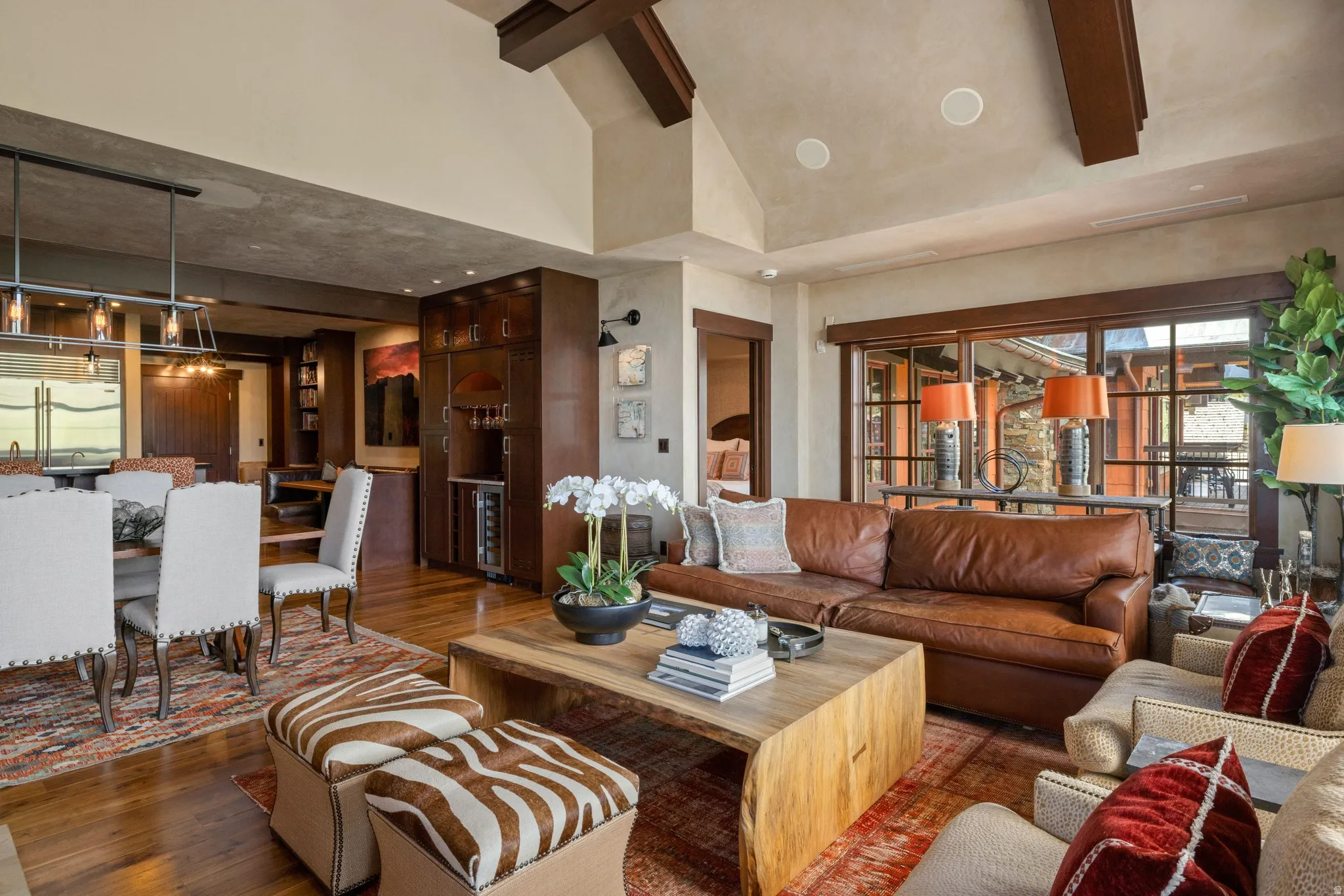 Wood-finish flooring throughout, vaulted ceiling with exposed beams, and a built-in wet bar with a wine refrigerator