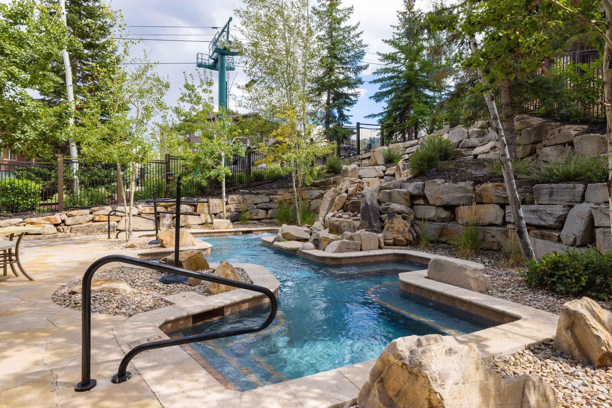Water feature with tiered rock landscaping, integrated spa, and natural stone accents