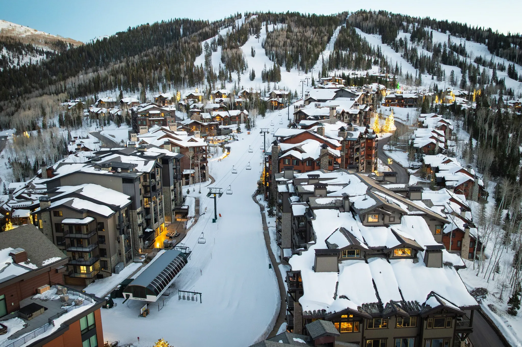 Mountain resort community featuring multiple residential structures with varied architectural styles, snow-covered roofs, and visible ski slopes