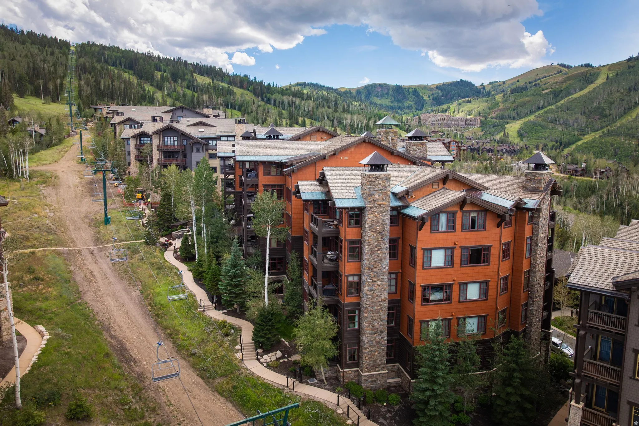 Multi-story property featuring wood siding and stone chimney accents