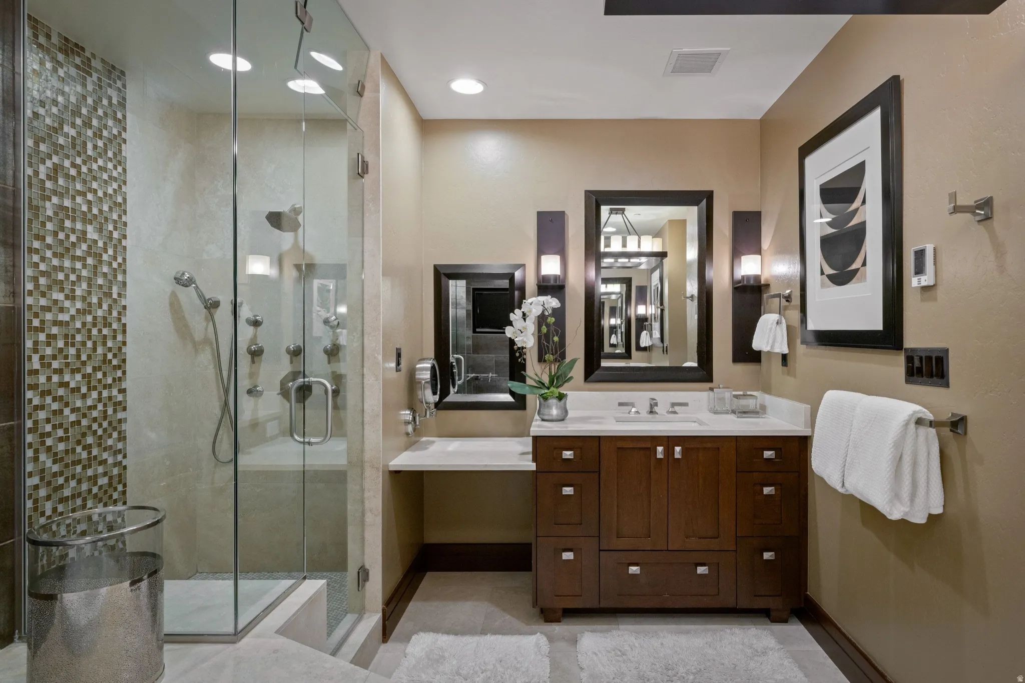 Glass-enclosed shower with multiple shower heads and mosaic tile accents